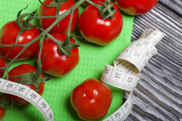 Wall Mural - Bunches of tomatoes are on the scales. Near the measuring tape. On brushed pine boards. Symbol of World No Diet Day.