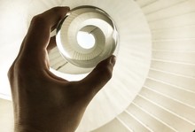 Cropped Hand Of Woman Holding Crystal Ball Over Spiral Staircase