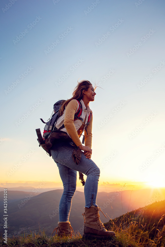 Portrait of happy young woman hiking in the mountains - obrazy, fototapety, plakaty 