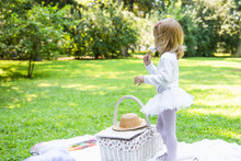 A Little Beautiful Girl Walks In The Park With A Picnic Basket And Straw Hat. Funny Emotional Baby.