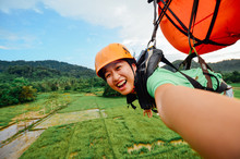 Portrait Of Smiling Woman Parasailing Over Field