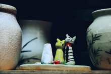 Close-up Of Figurines And Pot On Table