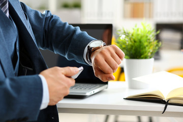 Man in suit and tie check out time at silver wristwatch closeup. Show and point with finger waste minute modern punctual life style start hurry job idea last second clockwork precision concept