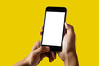 © NINENII - Hand holding white mobile phone with blank white screen Yellow background.