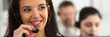 © H_Ko - Three call centre service operators at work. Portrait of smiling pretty brunette woman at workplace employment effective mediation negotiation participation solve problem real time aid job concept