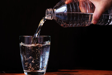 Wall Mural - Pouring water in glass on a wood background