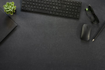 Top view of black concrete office desk with computer and supplies