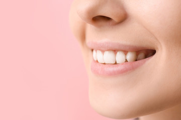 Young woman with healthy teeth on color background, closeup