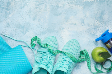 Yoga mat, sport shoes, bottle of water and apple on color background. Weight loss concept