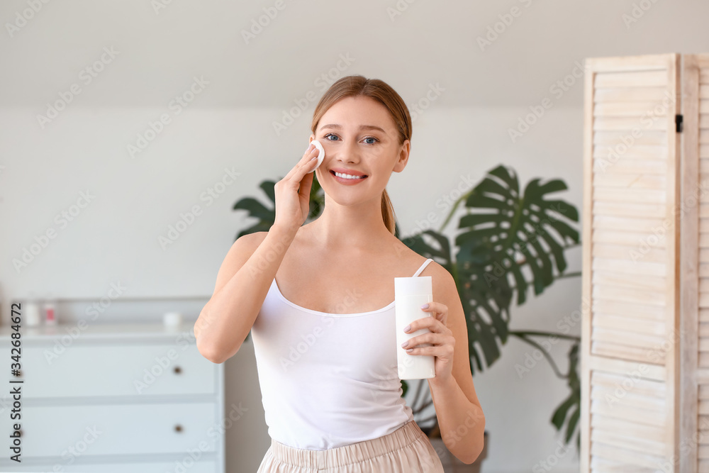 Beautiful young woman removing makeup at home