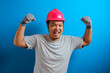 © Reza - Portrait of funny fat Asian man wearing red helmet smiling proudly while showing double biceps pose, strength over confidence concept