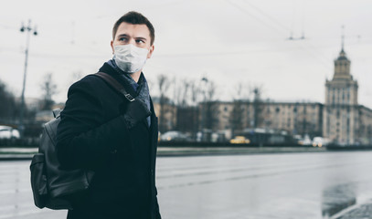 Quarantine in Russia in 2020. Prevention of coronavirus outbreak. Close up portrait of young russian man wearing a mask at Moscow street. Prevent pollution and disease concept