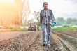 © ElitProd - Portrait of a woman farmer walking in the  field in front of the tractor