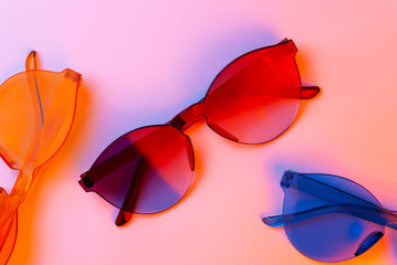 Wall Mural - Colored glasses in neon light for night party, plastic hipster glasses on colored background