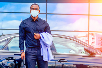 successful businessman handsome African American man in a stylish suit in a blue jacket standing in front of a cool new black car on the street