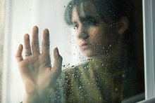 The Girl's Palm Is On Glass With Drops And Blurred Portrait Of Beautiful Girl In Military Retro Uniform Behind  The  Window . The Concept Of Romantic, Love During War, Waiting For Peace.
