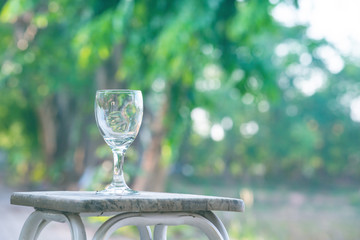 Water splash in glass Select focus blurred background.Drink water pouring in to glass over sunlight and natural green background.Nature conservation concept.