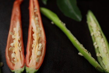 Red and Green chilli pepper sliced length-ways on wooden dark board. 