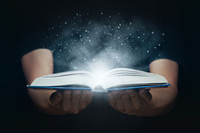Man Open Magic Book With Growing Lights And Magic Powder Floating On The Book, Learning, Education, Knowledge And Religion Concept.