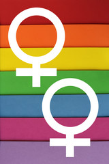 Two white female symbols. Background in the colors of LGBT flag. Texture sheets of paper of red, orange, yellow, green, blue, purple.  LGBT concept, symbol of LGBT, Background poster, banner, card