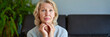 © JENOCHE - middle-aged blond woman sitting on a sofa at home