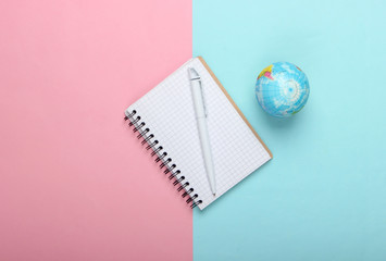 Wall Mural - Globe and notebook on pink blue pastel background. Top view. Minimalism. Education concept, geography