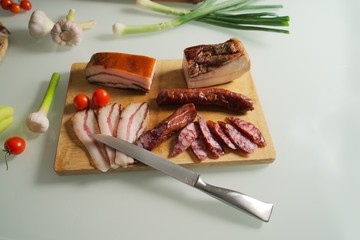 Knife on the table with pork meat delicacies, prosciutto, lard, sausage, Bavarian sausages