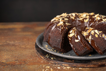 Sweet Homemade Dark Chocolate Bundt Cake with almonds over dark background, copy space. Selective focus. Ready to Eat.