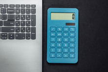 Calculator And Laptop On Black Background. Top View