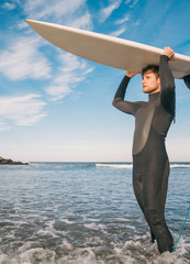 Young surfer holding up his surfboard.