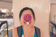 Happy Young Woman Holding Smiley Face Lollipop At Restaurant