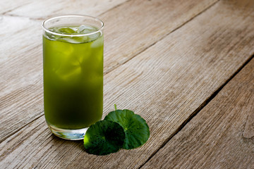 Wall Mural - Closeup cup glass of Gotu Kola tea with green leaves ( Asiatic pennywort, Indian pennywort, Centella asiatica ) isolated on wood table background. Tropical medical herbal plant, healthy drink concept 