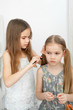 © andrey - little girl makes ponytails of her younger sister