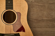 Acoustic guitar body with a red pick guard put down on a brown wooden floor