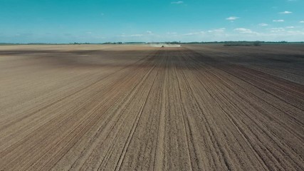 Wall Mural - Tractor in the dust working in the field. Tractor cultivating field, kicking up rocks and dust in the early morning.  Aerial view of tractor on Prepare a field for planting, top view
