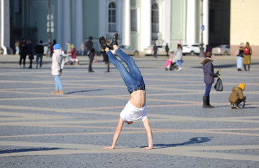 A young man stands on his hands, Palace square, Saint Petersburg, Russia, March 2020