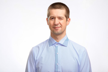 confident successful winking man closed one eye, wearing a blue shirt, staring at the camera. Isolated