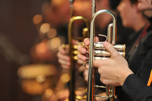 Trumpet Held By Trumpeter Waiting His Turn, With Other Trumpets Out Of Focus Behind