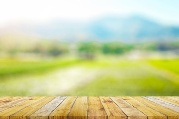 Shelf of Brown wood plank board with blurred green rice field farm with mountain and hut nature background.