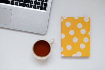 Study workspace: agenda, laptop and tea. Minimalist office, flat lay perspective. Top down