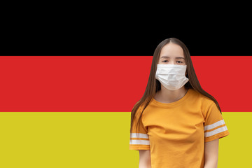 Wall Mural - Coronavirus in Germany. Young girl in antibacterial medical mask on a flag background with copyspace