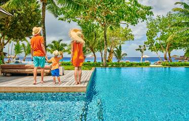 Canvas Print - Family of three by poolside. Resort swimming pool at Seychelles.