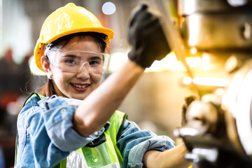 Wall Mural - Woman worker wearing safety goggles control lathe machine to drill components. Metal lathe industrial manufacturing factory