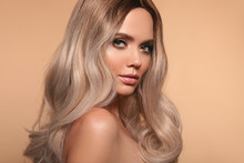 Ombre Blond Wavy Hairstyle. Beauty Fashion Blonde Woman Portrait. Beautiful Girl Model With Makeup, Long Healthy Hair Style Posing Isolated On Studio Beige Background.