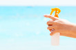 © sosiukin - Croped image of woman's hand holding sunscreen spray at the sea background