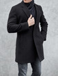 © AlexGo - man stands wearing black coat at gray background. young man in classic clothes.