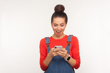 Wall Mural - Awesome mobile app! Portrait of social media user, girl reading message on cellphone with amazed surprised face, chatting typing blog post, browsing web on mobile phone. studio shot, white background