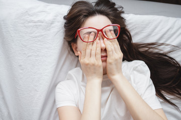Wall Mural - Young woman rubs her eyes after using glasses. Eye pain concept, poor vision.