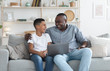 © Prostock-studio - African Grandfather And Grandson Using Laptop Together, Watching Movie At Home
