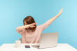 Dabbing trends. Overjoyed woman showing dab dance gesture, performing internet meme of success, sitting at workplace with laptop, home office job. indoor studio shot isolated on blue background